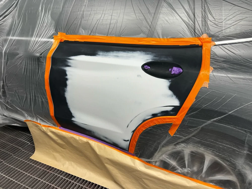 Vehicle door masked and prepared for refinishing